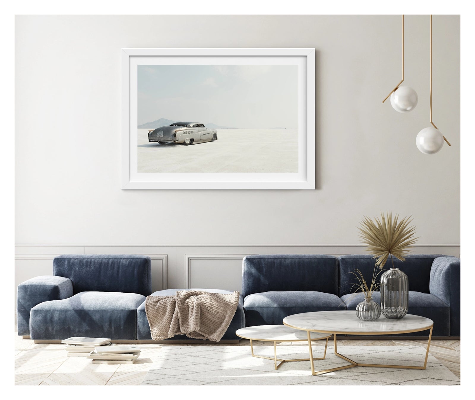 Framed in white, hanging in a contemporary living space. We see a rear three quarter view of a bare metal 1950s Buick landspeed race car sits low as it leaves the startline of the Bonneville Salt Flats, its chopped and channelled body heading towards nothingness. The bare metal bodywork and sculptural streamlined shape give the car an otherworldly, timeless presence against the vast white emptiness surrounding it. Fine art colour photographic print by Simon Davidson. 