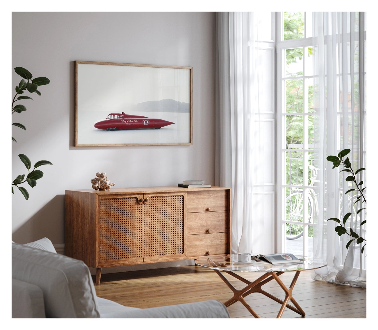 Framed in timber, hanging in a contemporary living space. A red vintage streamliner named City of Salt Lake and sponsored by STP and Firestone sits on the Bonneville Salt Flats, its long streamlined shaped body tapering to a sharp nose point with a small raised cockpit canopy above. The elegant mid century streamliner form glows deep red against the bleached white salt and pale hazy mountains dissolving into the horizon behind it. Fine art colour photographic print by Simon Davidson.