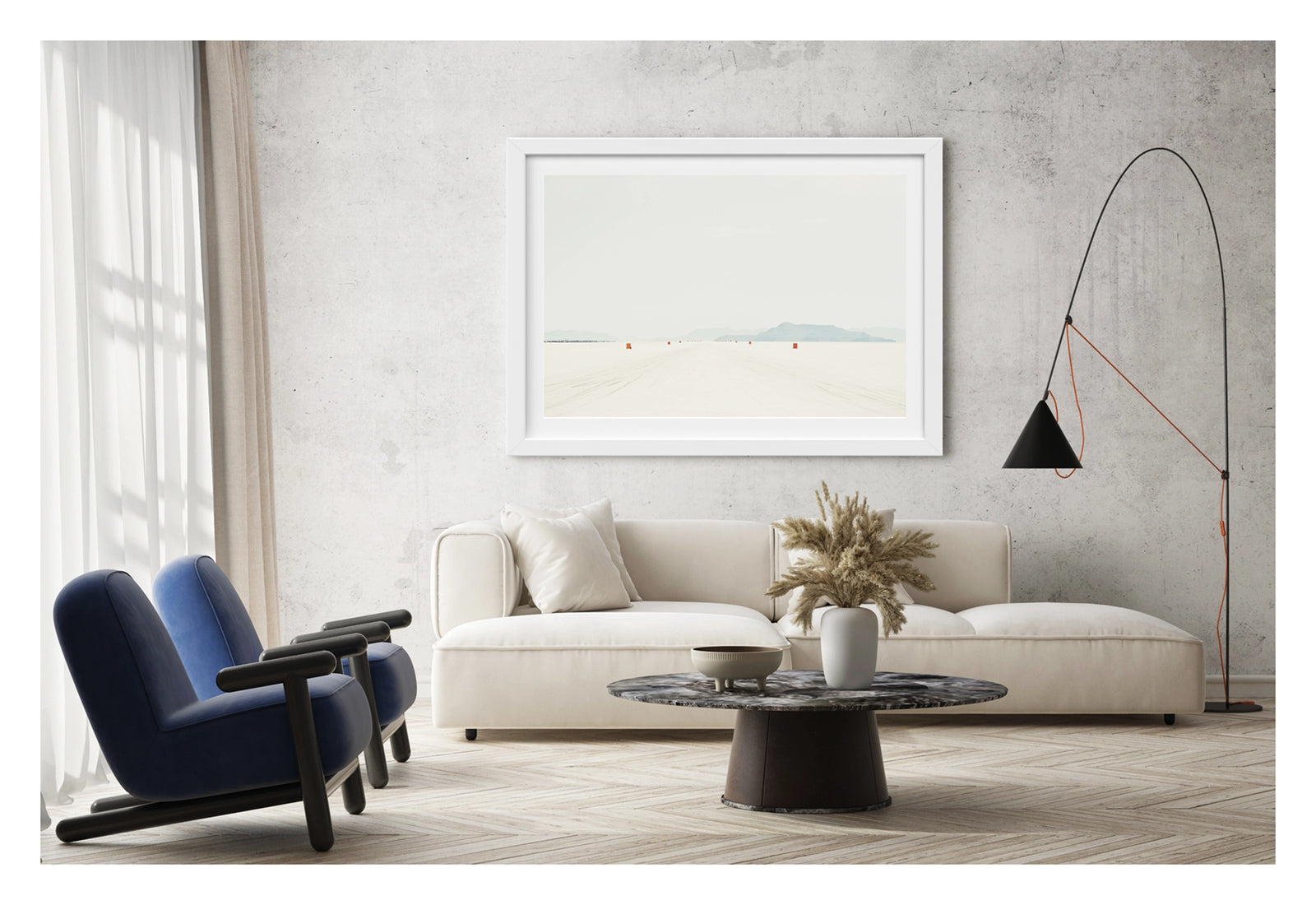 Framed in white, shown in a contemporary living space. We see a row of small orange course markers stretches into the vanishing point across the blinding white surface of the Bonneville Salt Flats, tyre tracks scoring the salt in the foreground as distant mountains dissolve into a pale grey horizon. The vast emptiness of the scene and the near seamless merging of salt flat and sky give the image a stark, minimalist beauty. Fine art colour photographic print by Simon Davidson.
