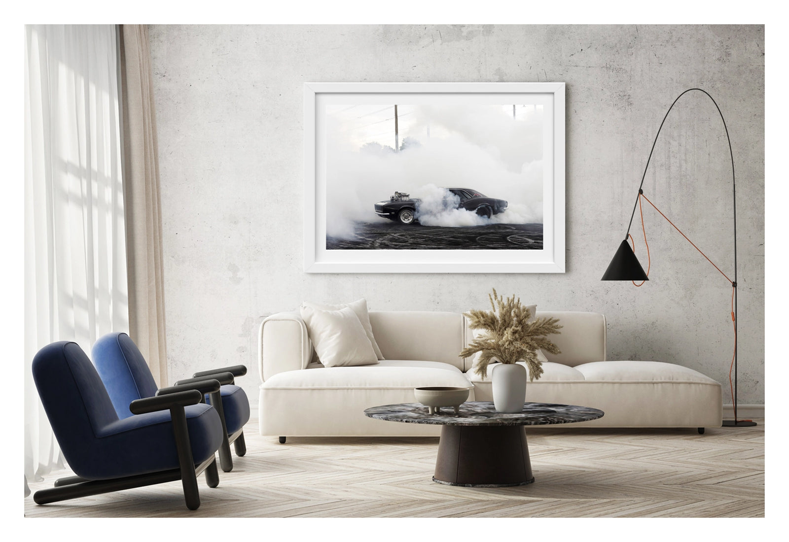 Framed in white, shown in a contemporary living space. We see a black Chevrolet Camaro with a polished supercharger protruding through the bonnet performs a burnout on a rubber streaked bitumen surface, engulfed in a thick cloud of white tyre smoke that erases the sky. Power lines and trees ghost through the haze in the background as the car sits at the centre of its own self made storm, wide slick tyres barely visible beneath the billowing smoke. Fine art colour photographic print by Simon Davidson.