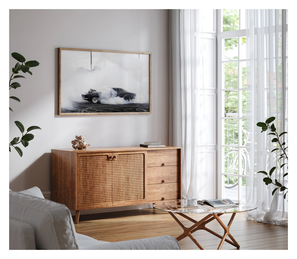 Framed in timber, shown in a contemporary living space. We see a black Chevrolet Camaro with a polished supercharger protruding through the bonnet performs a burnout on a rubber streaked bitumen surface, engulfed in a thick cloud of white tyre smoke that erases the sky. Power lines and trees ghost through the haze in the background as the car sits at the centre of its own self made storm, wide slick tyres barely visible beneath the billowing smoke. Fine art colour photographic print by Simon Davidson.