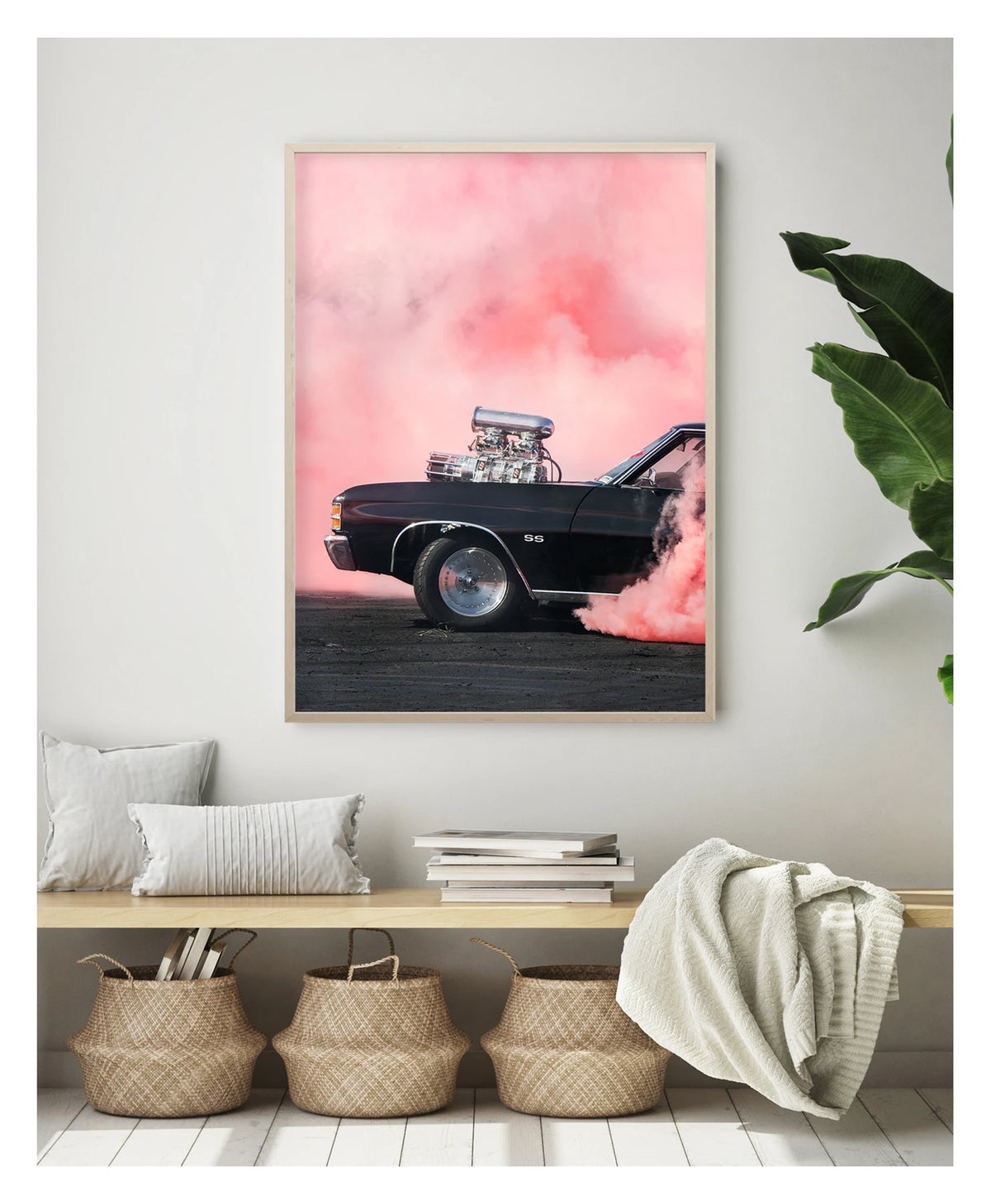 Framed in timber. A black Chevrolet Chevelle SS with a massive polished supercharger protruding through the bonnet performs a burnout, engulfed in vivid pink tyre smoke that fills the entire background. The chrome blower and intake manifold gleam against the dark body as thick pink smoke pours from the under the car onto the tyre marked scorched black bitumen. Showing the framed print in a contemporary space. Fine art colour photographic print by Simon Davidson.