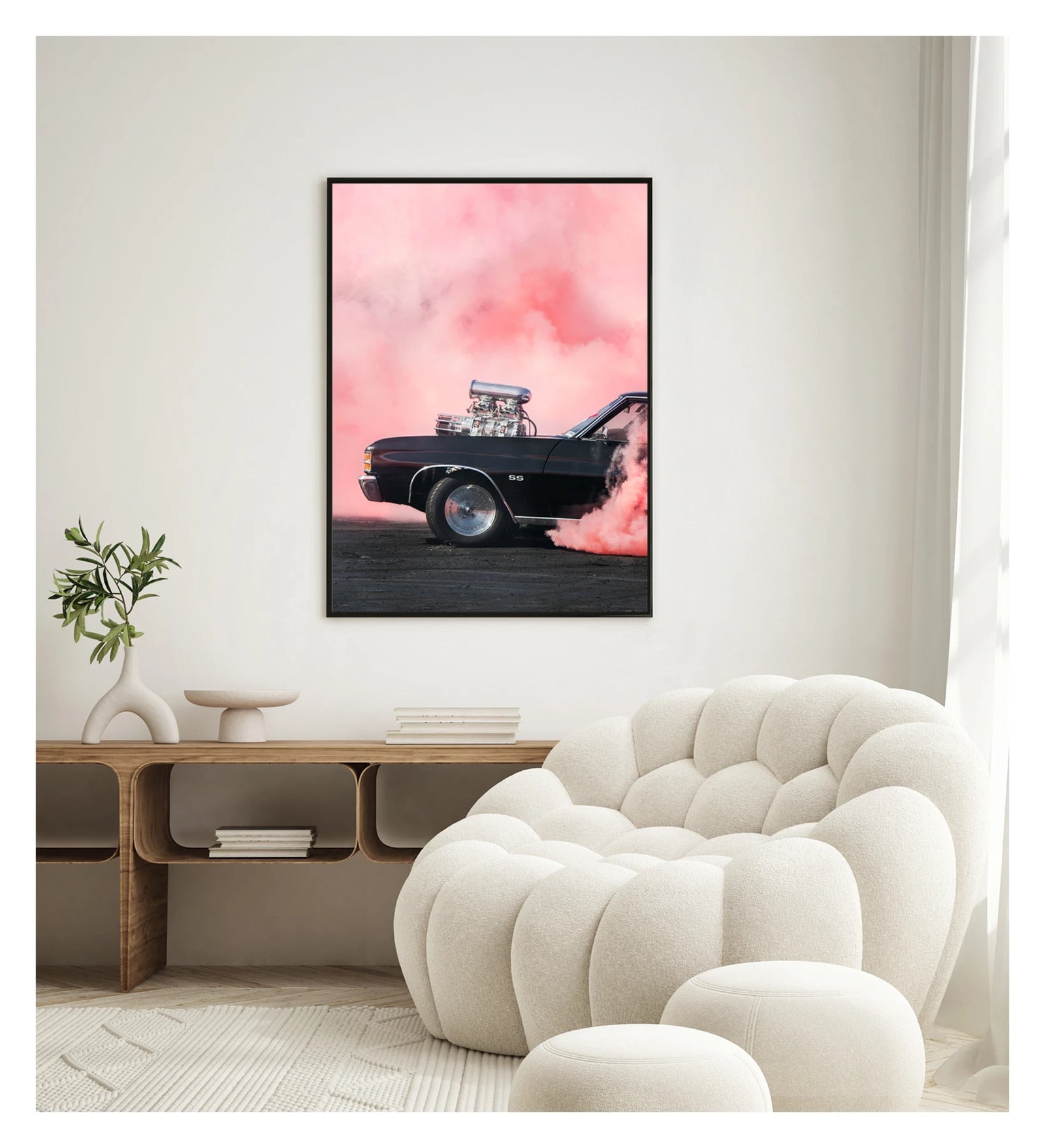 Framed in black. A black Chevrolet Chevelle SS with a massive polished supercharger protruding through the bonnet performs a burnout, engulfed in vivid pink tyre smoke that fills the entire background. The chrome blower and intake manifold gleam against the dark body as thick pink smoke pours from the under the car onto the tyre marked scorched black bitumen. Showing the framed print in a contemporary space. Fine art colour photographic print by Simon Davidson.