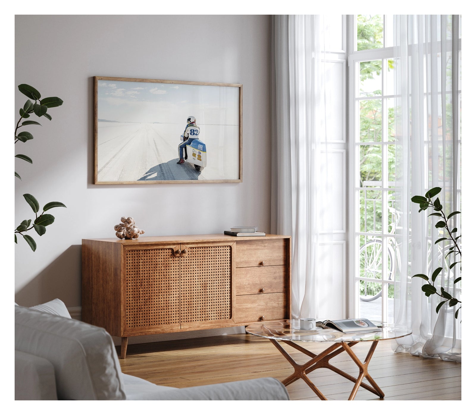 Framed in timber, shown in a modern space. A land speed motorcycle racer wearing a blue and yellow race suit numbered 82 sits astride a white streamlined motorcycle numbered 8282 on the Bonneville Salt Flats, facing away from the camera toward the long straight track that stretches to the distant mountains and pale horizon. Tyre tracks score the white salt surface at the start line as a soft blue sky with scattered clouds completes the vast open scene. Fine art colour photographic print by Simon Davidson.