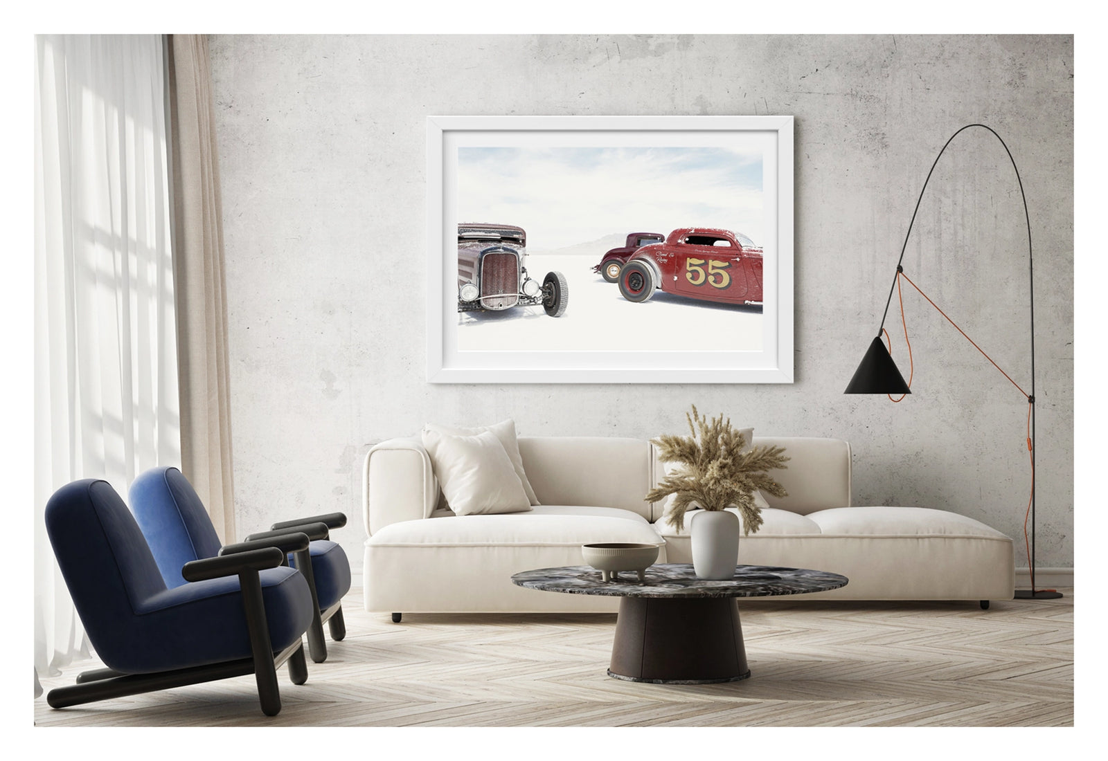 Framed in a white on a concrete wall. Two salt encrusted Rolling Bones hot rods sit on the blinding white surface of the Bonneville Salt Flats, their weathered bodies dusted with salt crystal residue. with a third maroon coupe visible between them in the middle distance. A pale mountain range dissolves into the white horizon behind them. Fine art colour photographic print by Simon Davidson.