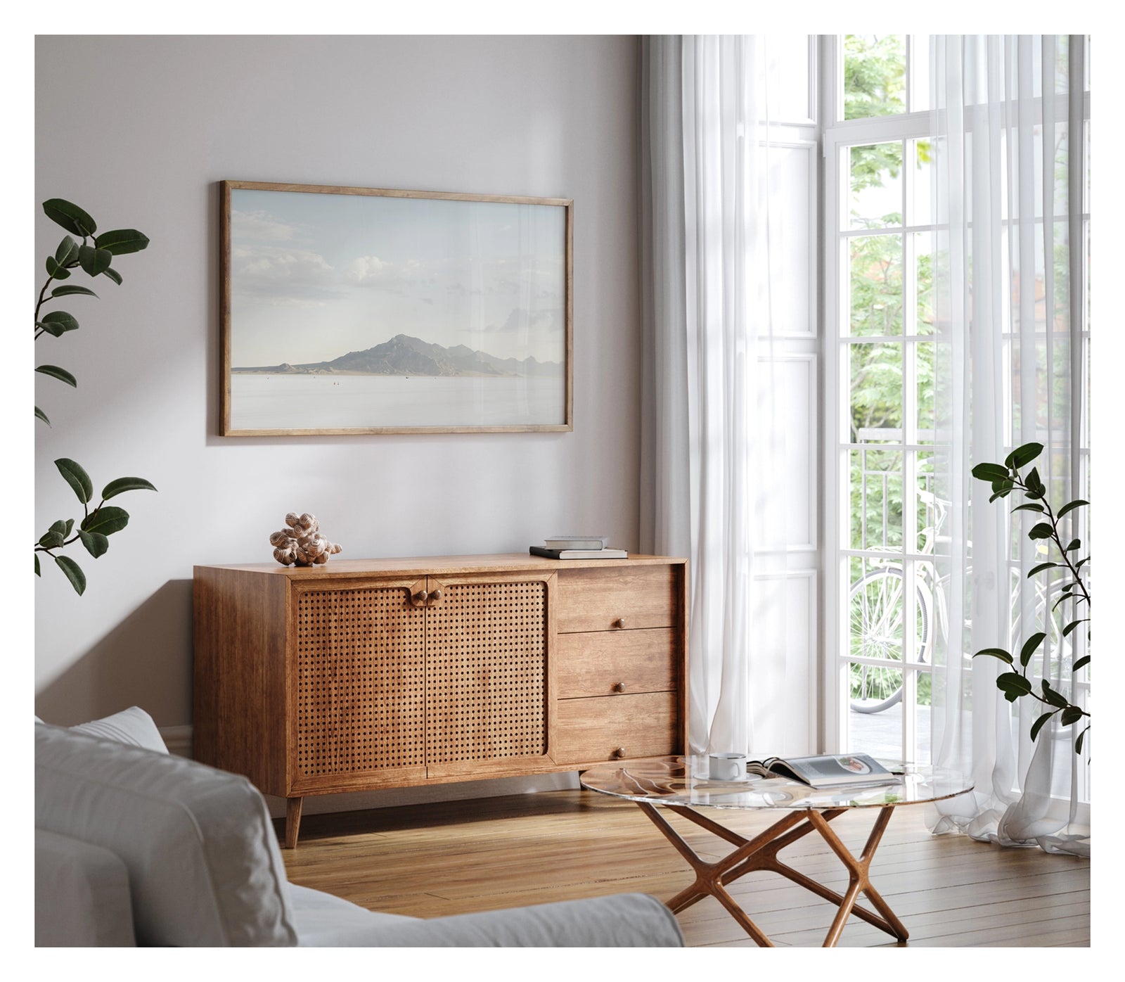 Framed in white, hanging in a contemporary living space. An image of the vast expanse of the Bonneville Salt Flats stretches towards the Silver Mountains, it's softened by haze beneath a pale blue sky of billowing cumulus clouds. Tiny orange cones dot the salt at the base of the mountain, their miniature scale emphasising the immense stillness and silence of the landscape. Fine art colour photographic print by Simon Davidson.