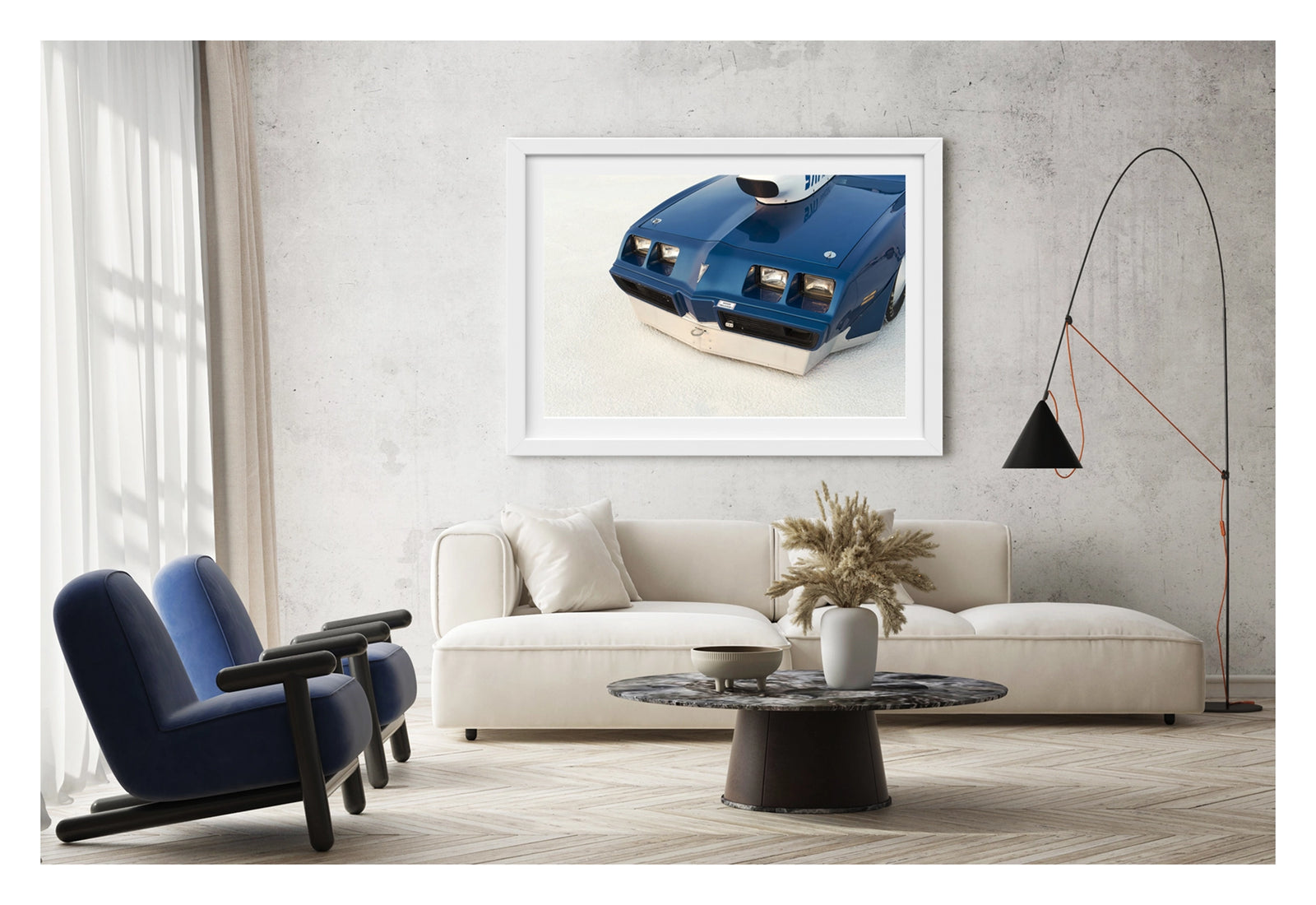Framed in white, hanging in a contemporary living space. We see a close up of the front end of a blue Pontiac Trans Am land speed racer sitting low on the white salt of the Bonneville Salt Flats, its distinctive quad headlights, Pontiac arrow nose and fabricated aluminium lower valance filling the frame. A streamliner style intake is visible above the bonnet line, the deep blue paint and salt crusted surface contrasting sharply in the crisp flat light. Fine art colour photographic print by Simon Davidson.