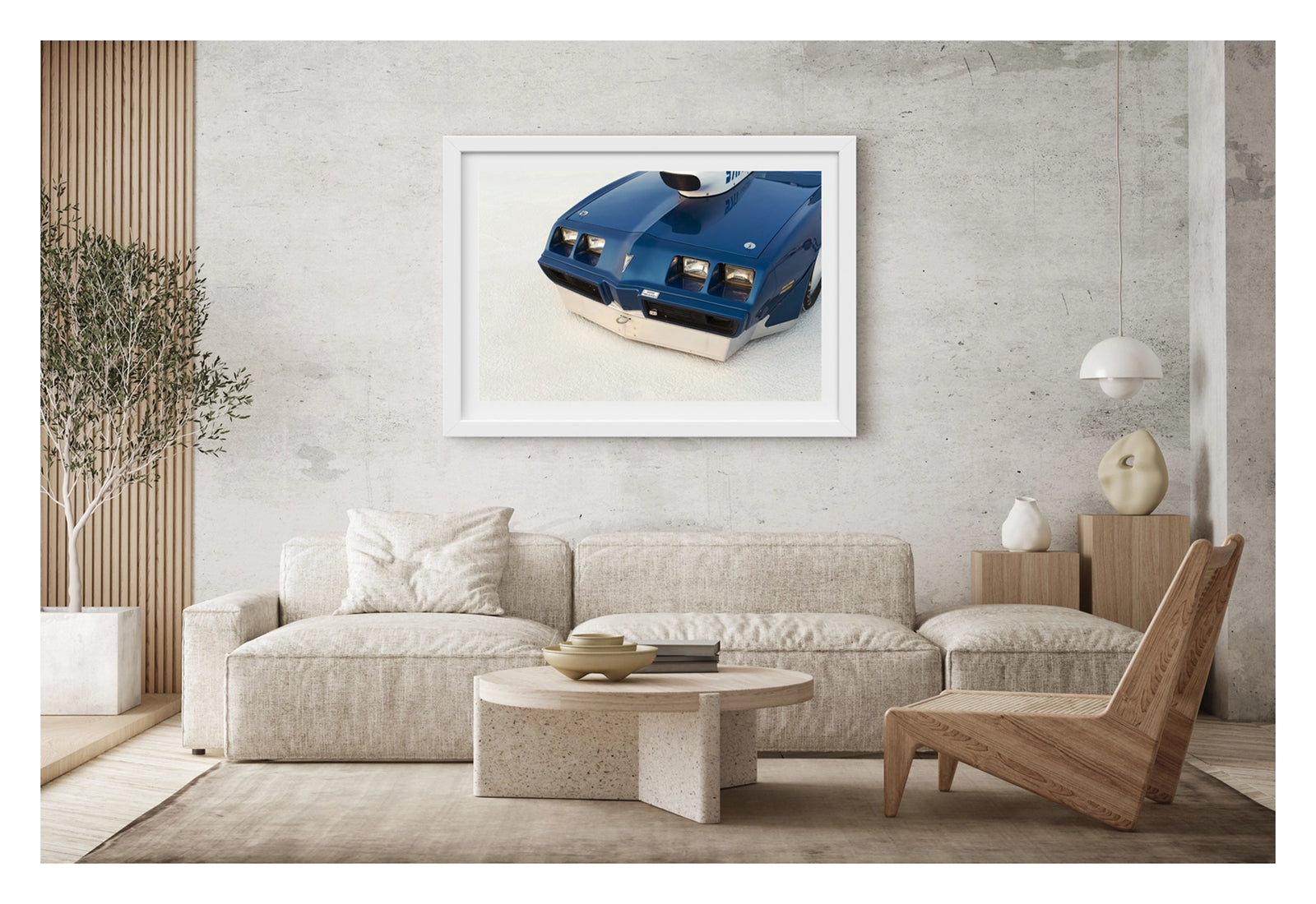 Framed in white, hanging in a contemporary living space. We see a close up of the front end of a blue Pontiac Trans Am land speed racer sitting low on the white salt of the Bonneville Salt Flats, its distinctive quad headlights, Pontiac arrow nose and fabricated aluminium lower valance filling the frame. A streamliner style intake is visible above the bonnet line, the deep blue paint and salt crusted surface contrasting sharply in the crisp flat light. Fine art colour photographic print by Simon Davidson.