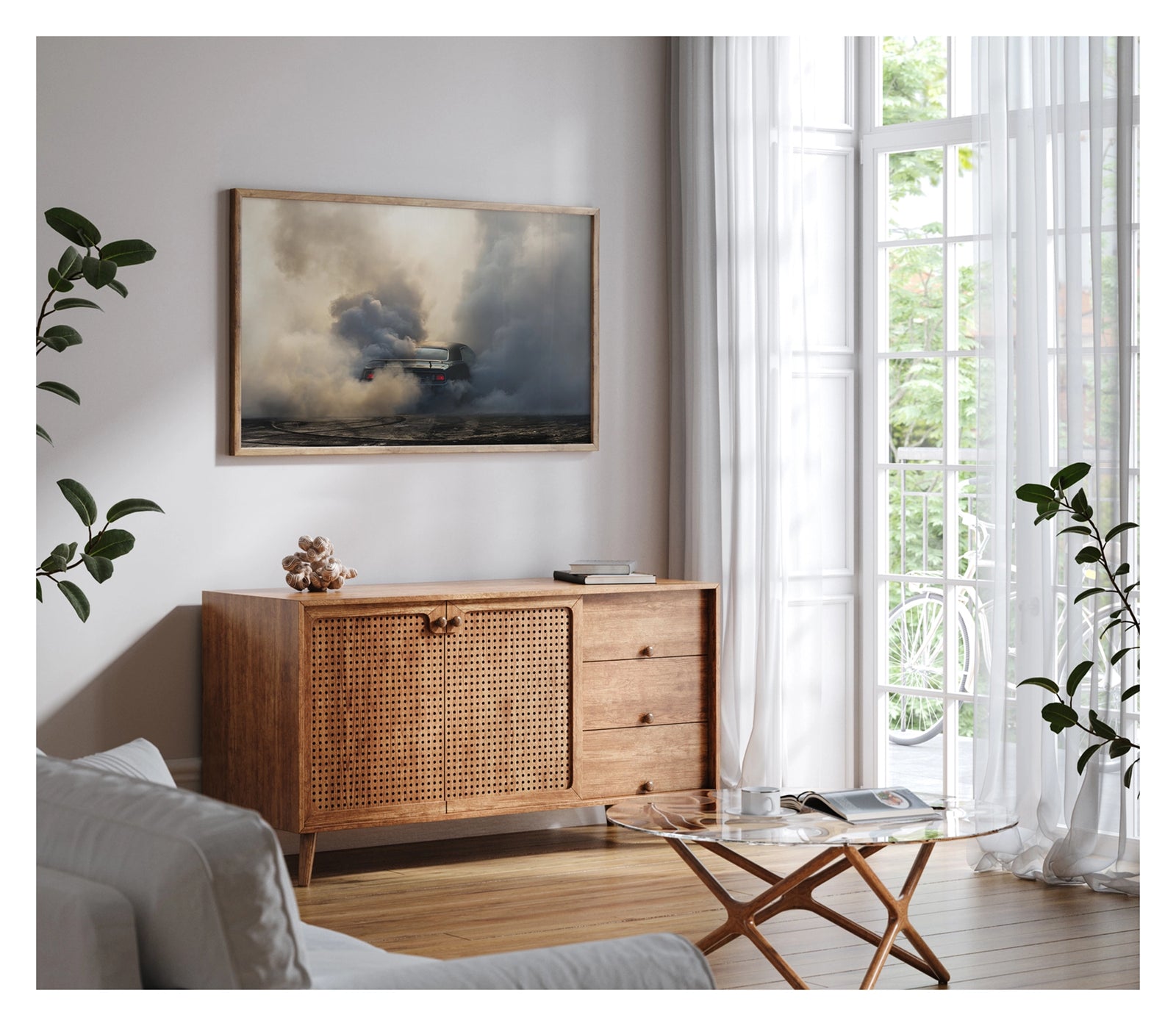 Framed in white, shown in a contemporary living space. We see the rear of a black Plymouth Barracuda with a vinyl roof performing a burnout, almost entirely consumed by billowing clouds of tyre smoke that fill the frame from ground to sky. Red tail lights glow through the haze, rubber marks streak the bitumen below. Fine art colour photographic print by Simon Davidson.