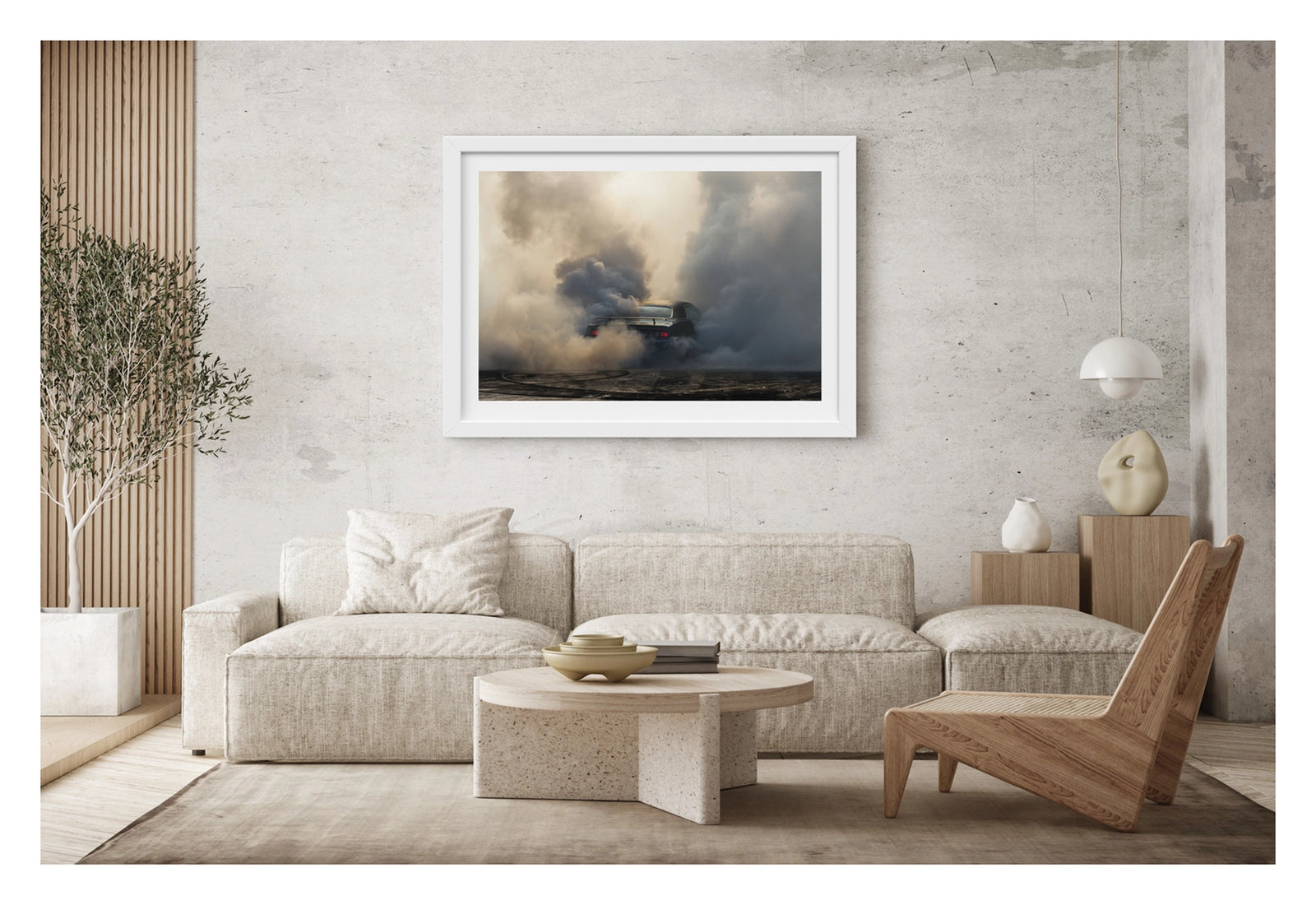 Framed in white, shown in a contemporary living space. We see the rear of a black Plymouth Barracuda with a vinyl roof performing a burnout, almost entirely consumed by billowing clouds of tyre smoke that fill the frame from ground to sky. Red tail lights glow through the haze, rubber marks streak the bitumen below. Fine art colour photographic print by Simon Davidson.