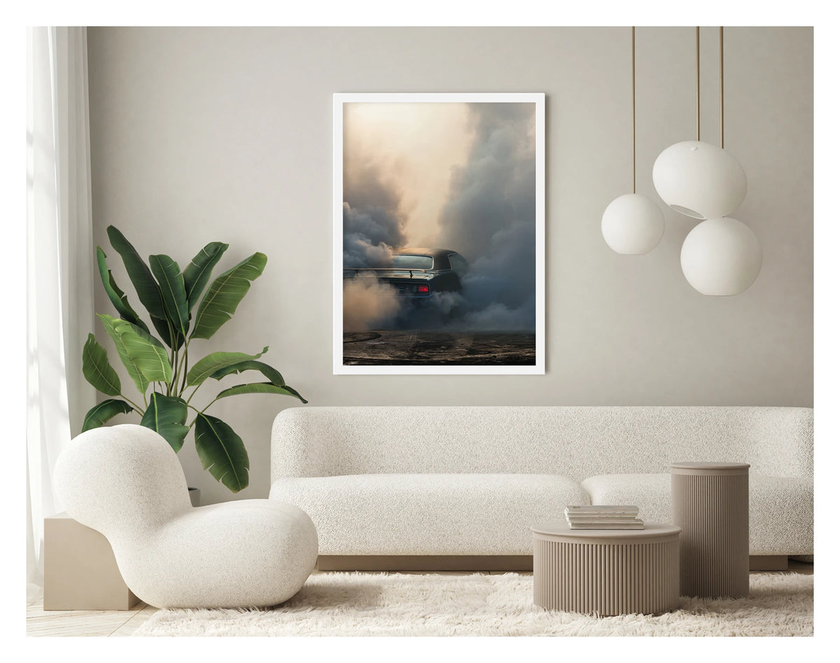Captured in a portrait orientation. Framed in white. We see the rear of a black Plymouth Barracuda with a vinyl roof performing a burnout, almost entirely consumed by billowing clouds of tyre smoke that fill the frame from ground to sky. A single red tail light glows through the haze as rubber marks streak the bitumen below. Fine art colour photographic print by Simon Davidson.