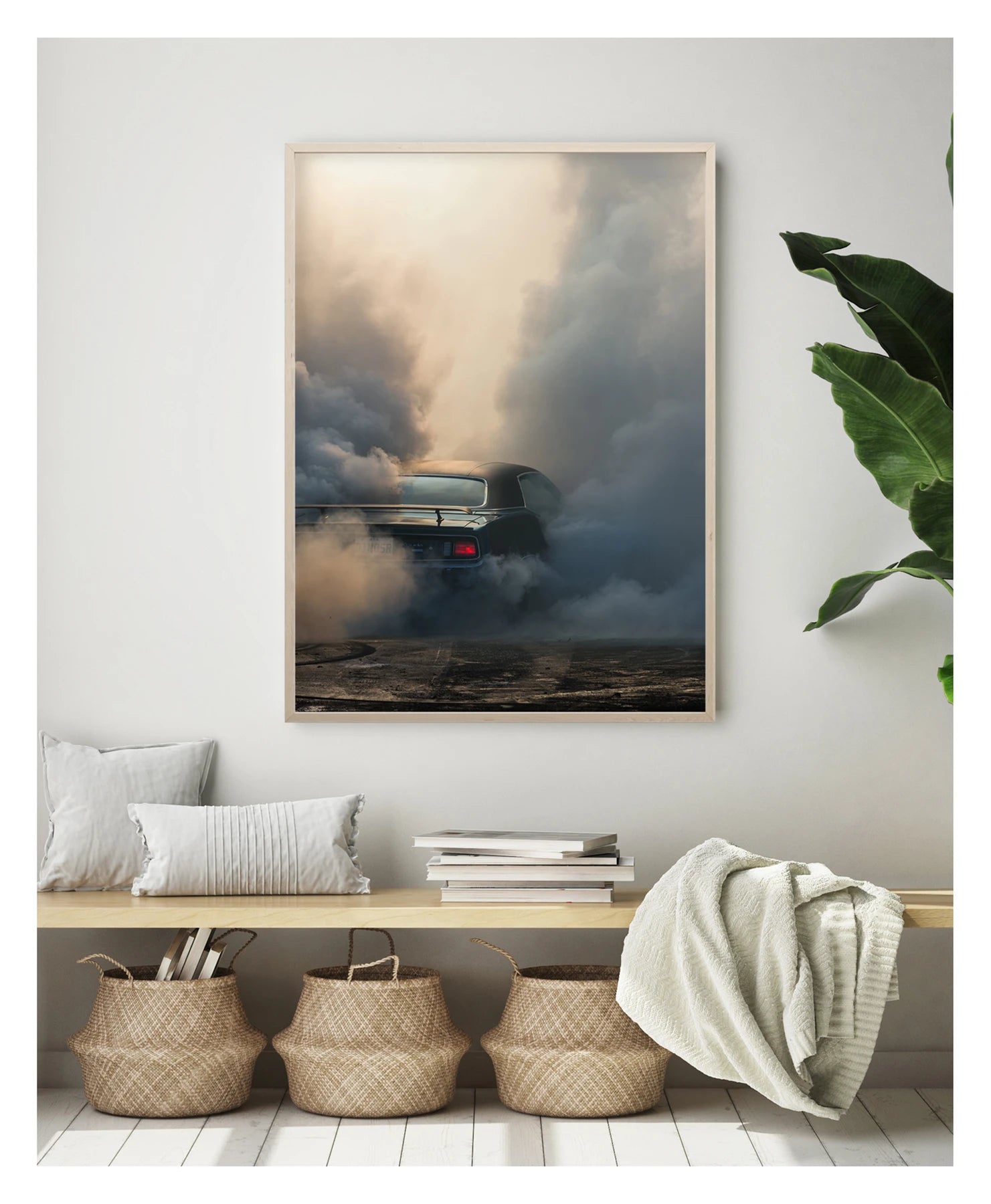 Captured in a portrait orientation. Framed in timber. We see the rear of a black Plymouth Barracuda with a vinyl roof performing a burnout, almost entirely consumed by billowing clouds of tyre smoke that fill the frame from ground to sky. A single red tail light glows through the haze as rubber marks streak the bitumen below. Fine art colour photographic print by Simon Davidson.