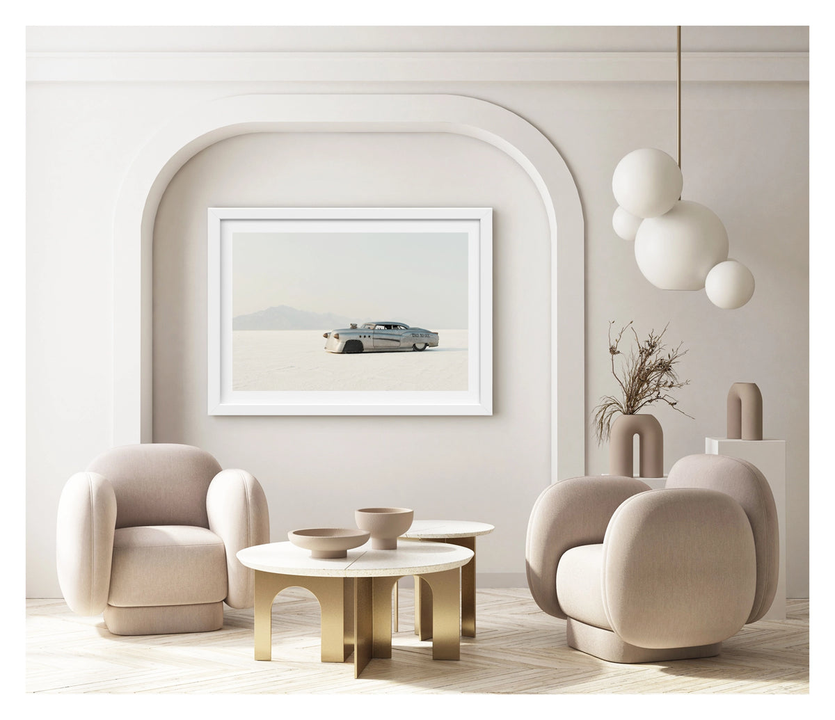 Framed in white, shown in a contemporary living space. A bare metal 1950s Buick land speed racer numbered 1503 sits low on the white salt of the Bonneville Salt Flats, its body heavily modified with covered wheel arches, bullet nose fairings, porthole details and a small blower poking through the bonnet. The unpainted aluminium bodywork gleams softly against the vast white salt and hazy mountain range dissolving into a pale grey sky behind it. Fine art colour photographic print by Simon Davidson.