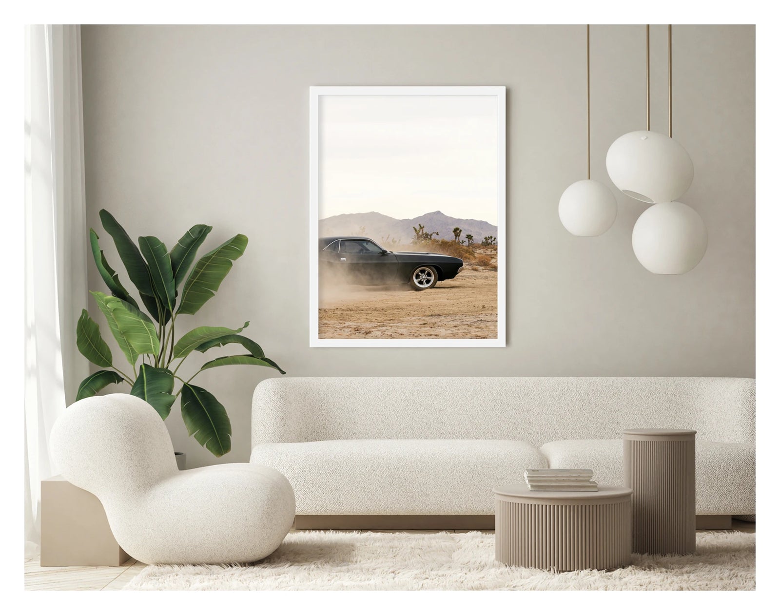 In a portrait orientation. Framed in white. A matte black first generation Dodge Challenger powers through a desert dirt surface, kicking up a low trail of dust from the rear wheels. Joshua trees and purple hue mountain ranges stretch across the horizon under a pale white sky, with the car's polished five spoke wheels and fastback roofline sharp against the hazy desert landscape. Shown in a contemporary space. Fine art colour photographic print by Simon Davidson.
