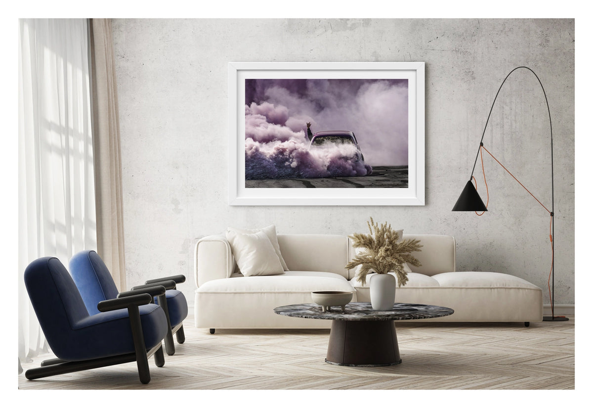 Framed in white, shown in a contemporary living space we see a purple Torana as it slides through the scene, rear to camera, is all but consumed by a vast billowing cloud of vivid purple smoke, with a passenger's arm thrust through the window throwing devil horns above the roofline as the only sign of human life within the haze. Fine art colour photographic print by Simon Davidson.