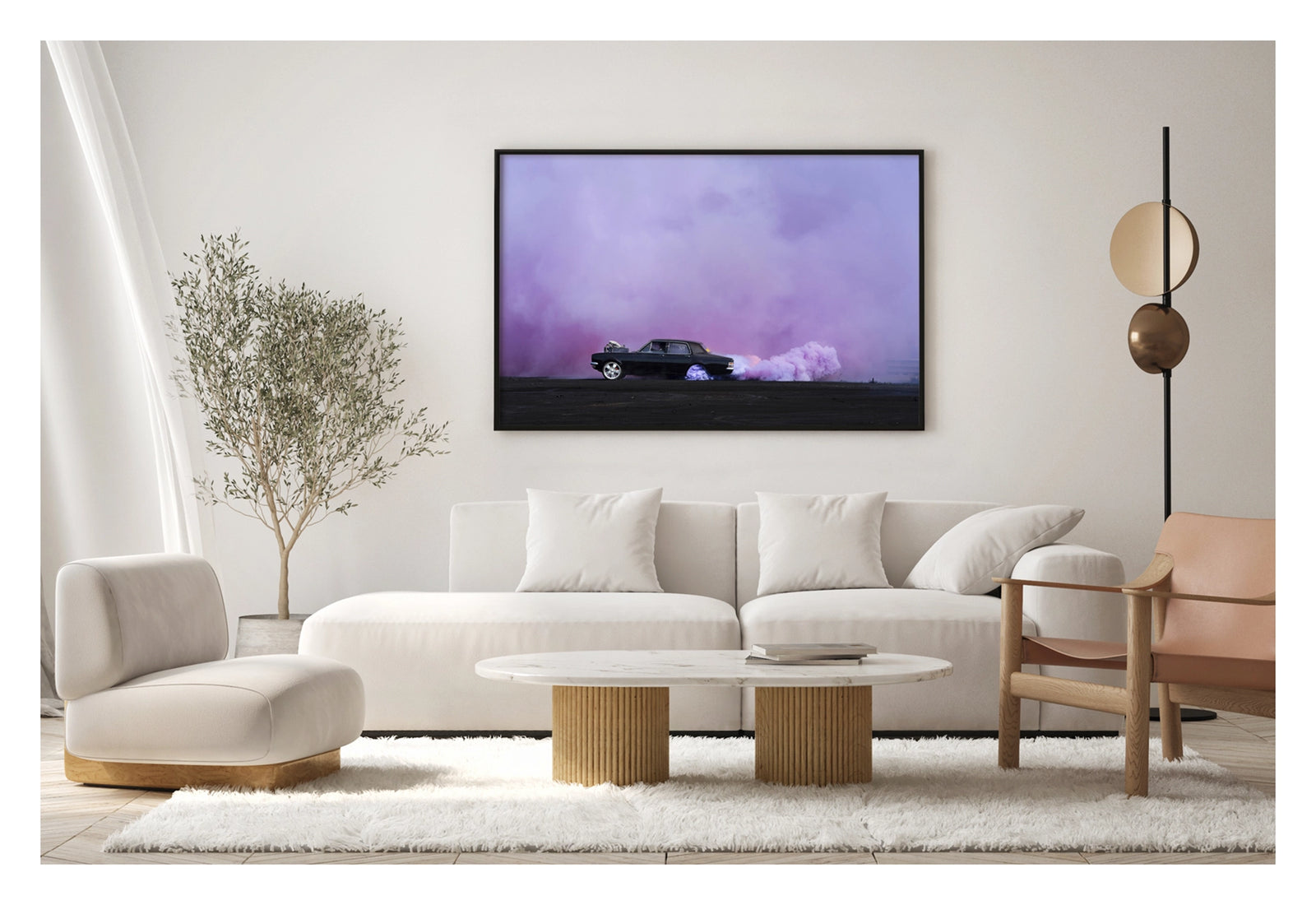 Framed in black, shown in a contemporary living space. A black Holden chrome bumper sedan with an exposed supercharger out the bonnet performs a burnout on a vast black bitumen surface, trailing a long rolling cloud of billowing purple tyre smoke that sweeps across the right side of the frame and fills the entire sky behind. The car sits small and sharp against the expansive purple haze, the scene feeling open and cinematic in its scale. Fine art colour photographic print by Simon Davidson.