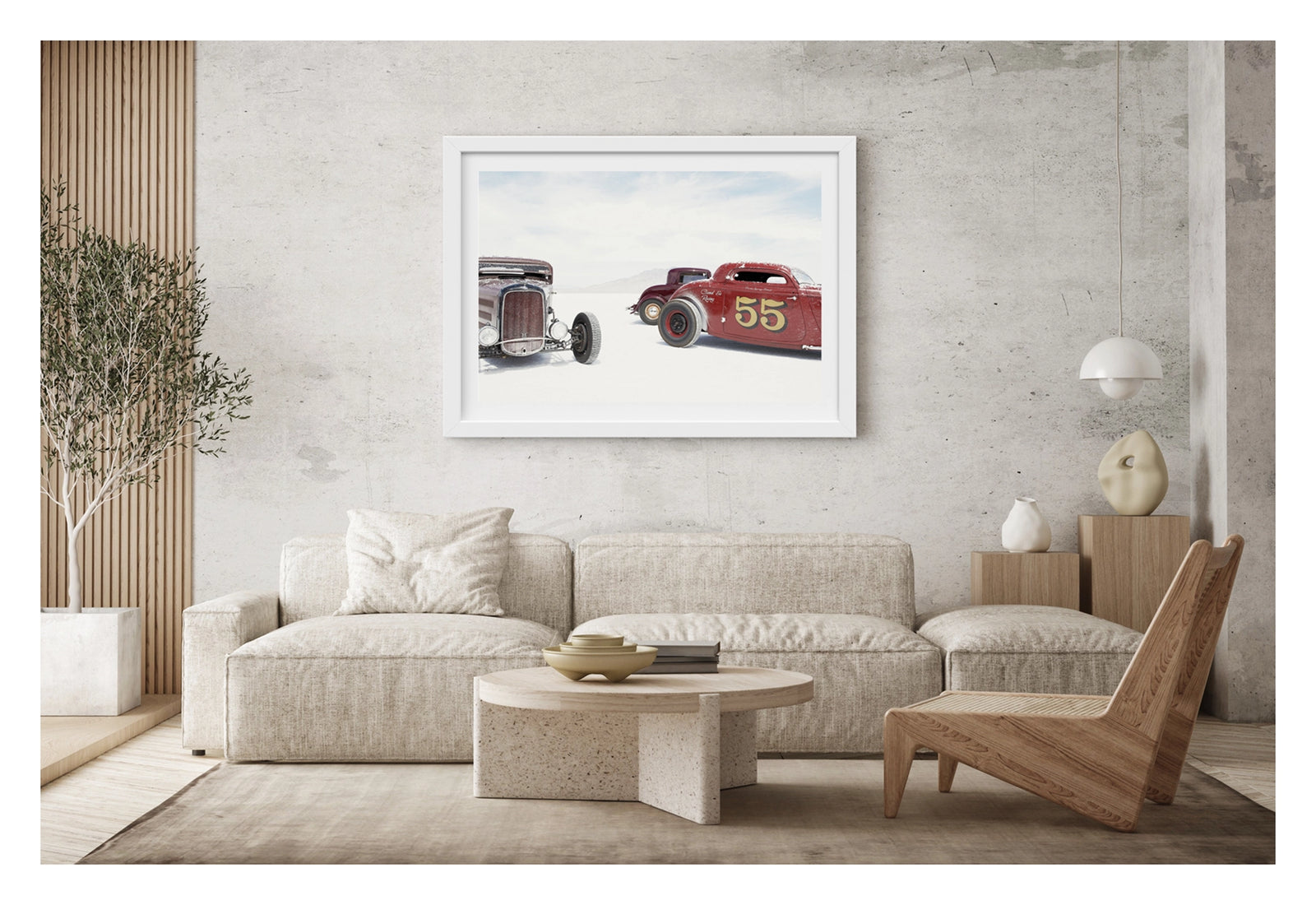Framed in a white on a concrete wall. Two salt encrusted Rolling Bones hot rods sit on the blinding white surface of the Bonneville Salt Flats, their weathered bodies dusted with salt crystal residue. with a third maroon coupe visible between them in the middle distance. A pale mountain range dissolves into the white horizon behind them. Fine art colour photographic print by Simon Davidson.